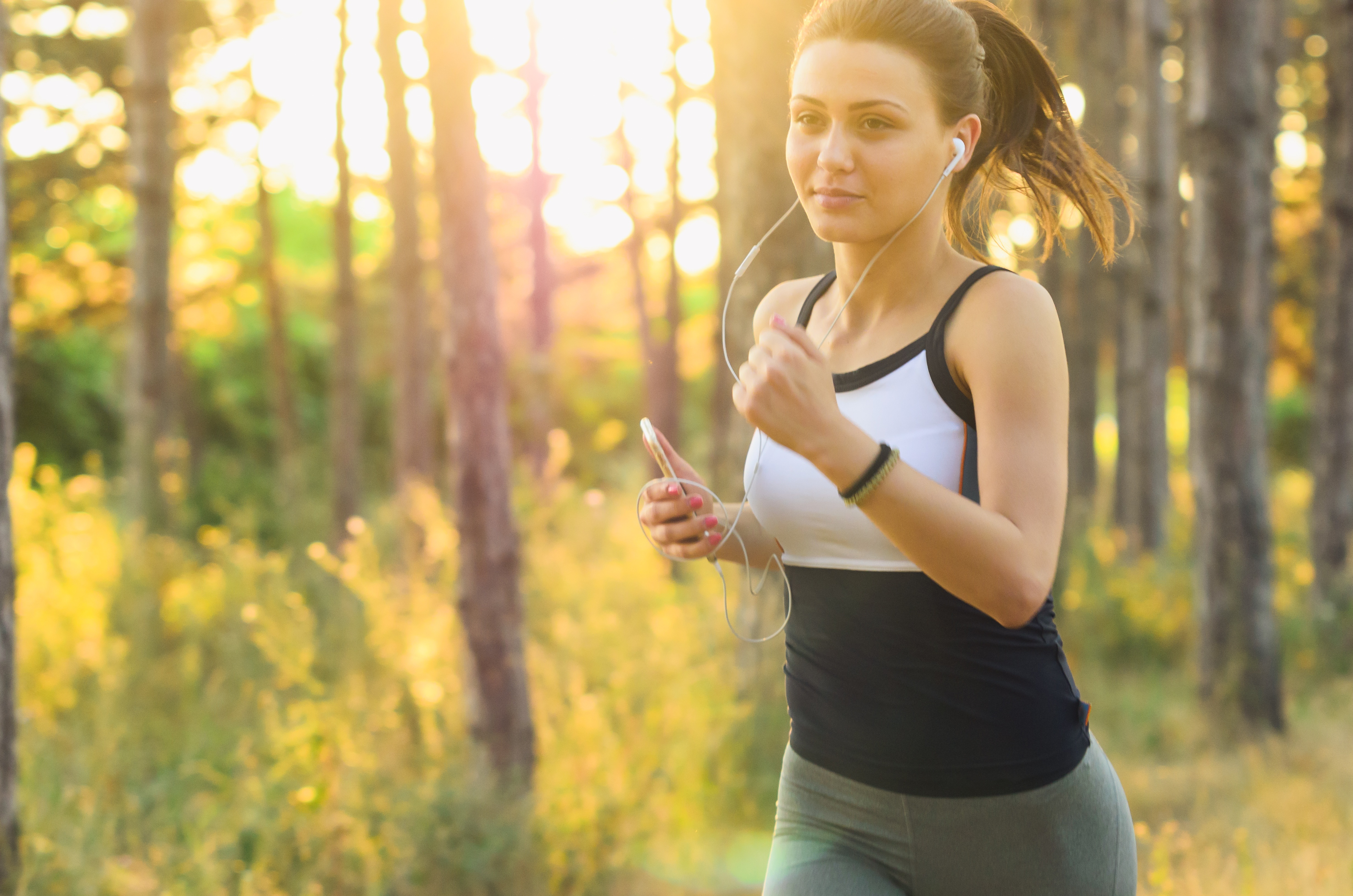 Hilft Sport bei Migräne. Junge Frau die durch den Wald joggt